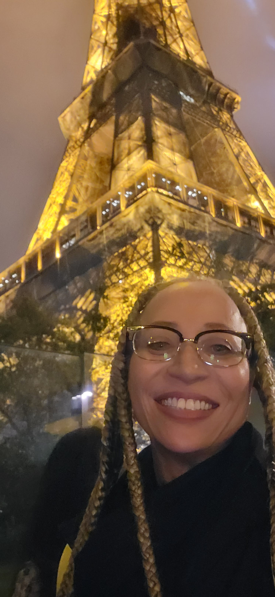 Allison smiling beneath the illuminated Eiffel Tower at night