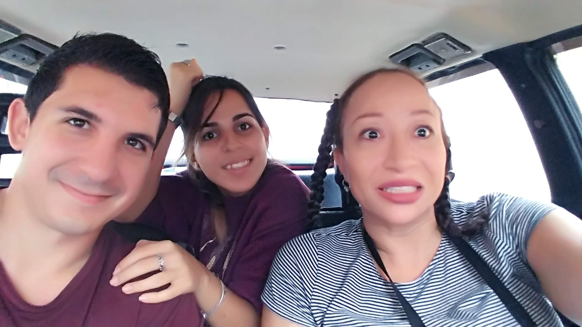Allison making a playful expression with two companions during a car ride in Havana