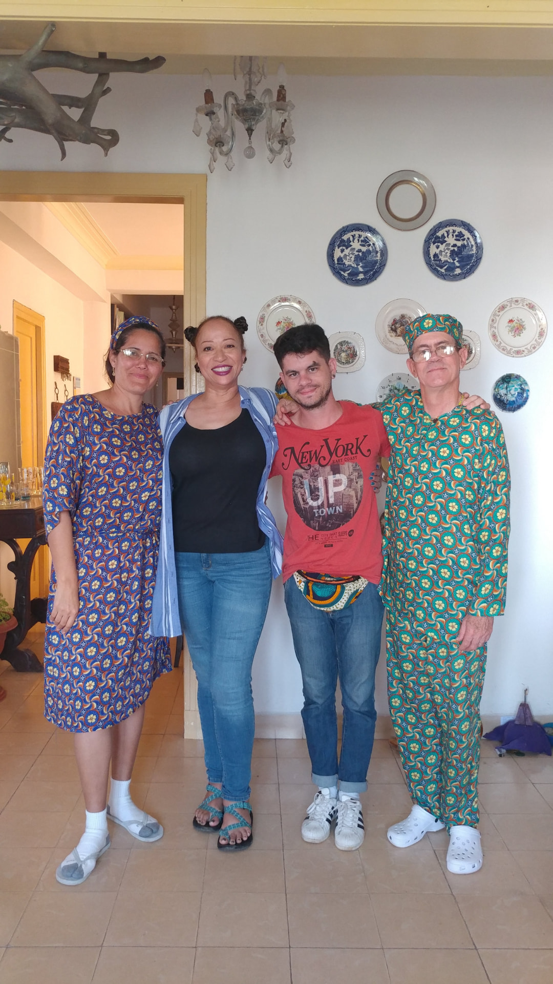 Allison and three companions standing beneath a collection of decorative plates in a Havana home