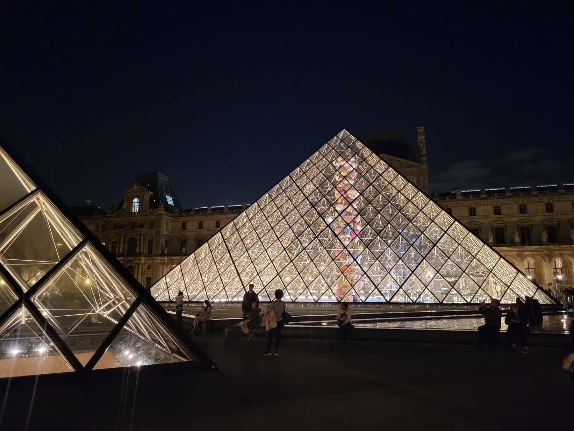 The Louvre pyramid lit from within against the night sky