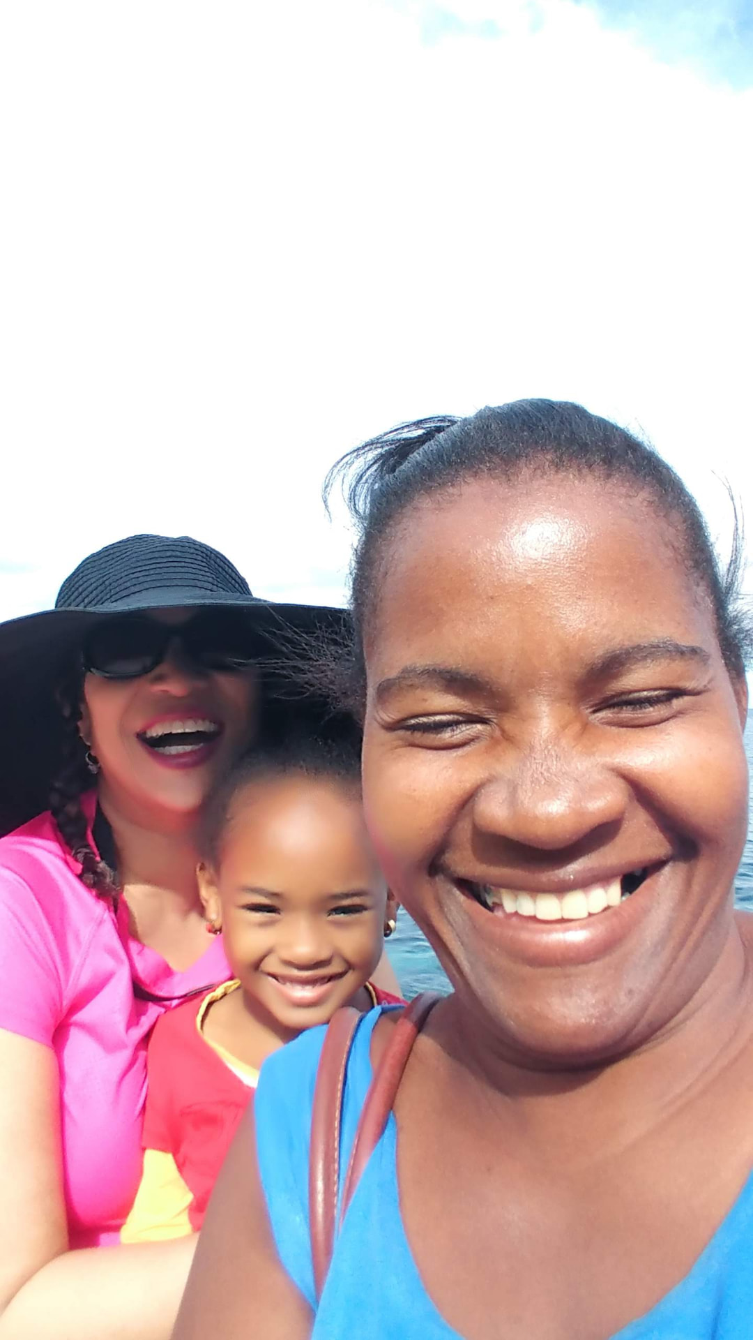 Allison smiling behind a woman and child during a sunny boat ride in Havana
