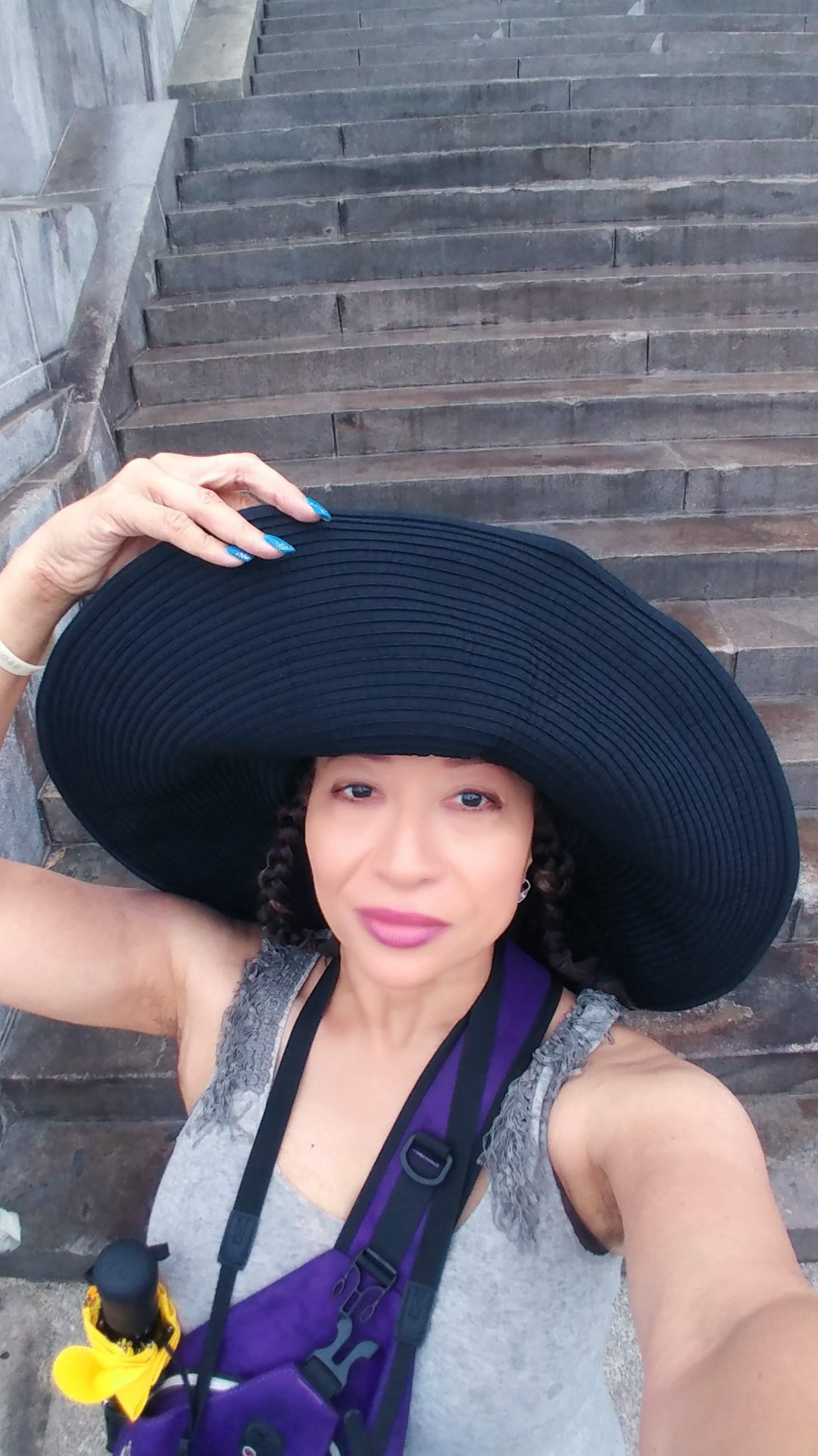 Allison in a wide black hat posing on broad stone steps in Havana